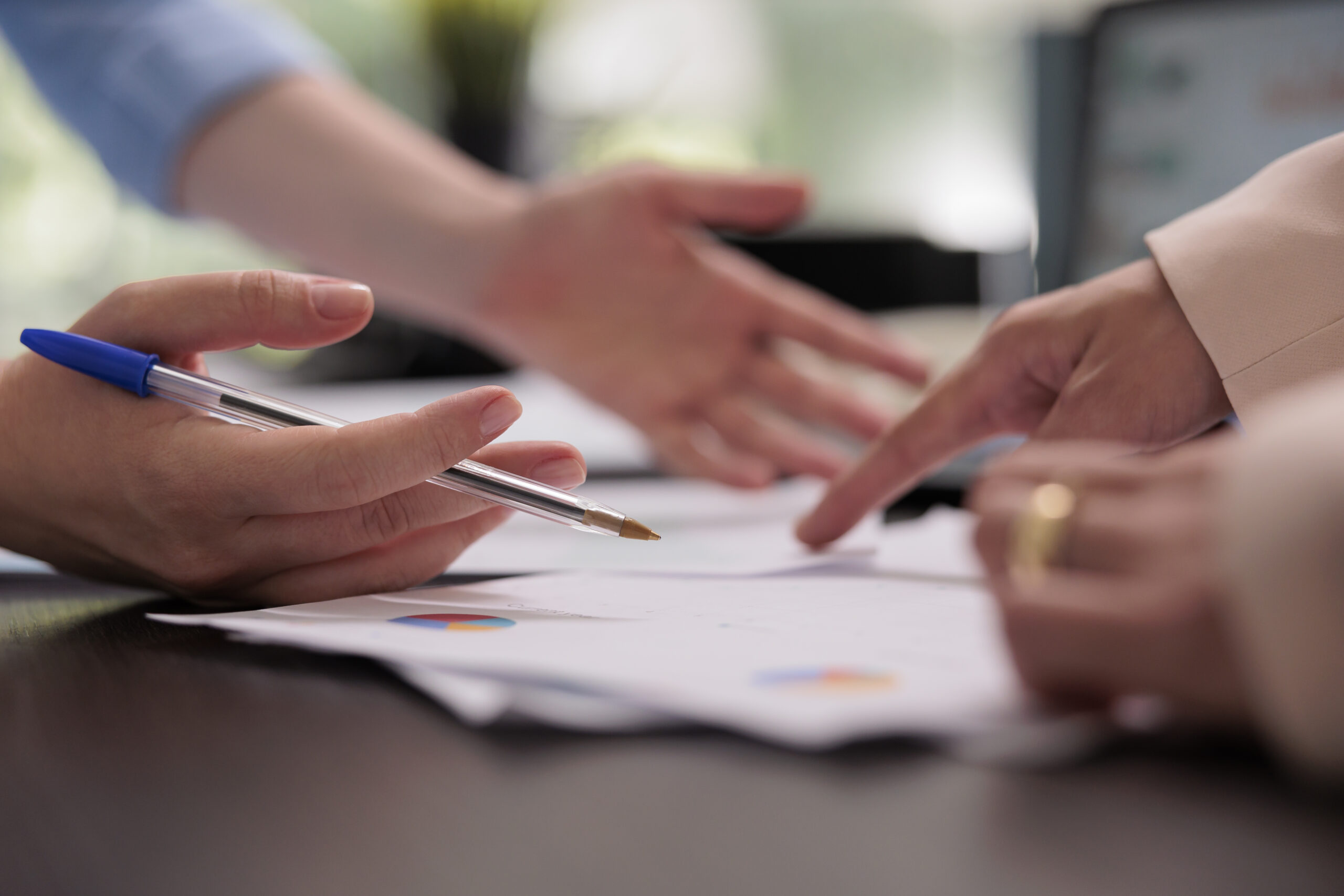 Coworkers analyzing financial report on meeting, planning company budget, close up on hands, woman pointing on charts. Colleagues teamwork, start up project investement briefing concept